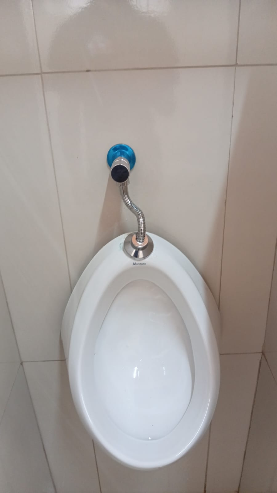 Mictório instalado na parede com válvula e engate flexível cromado