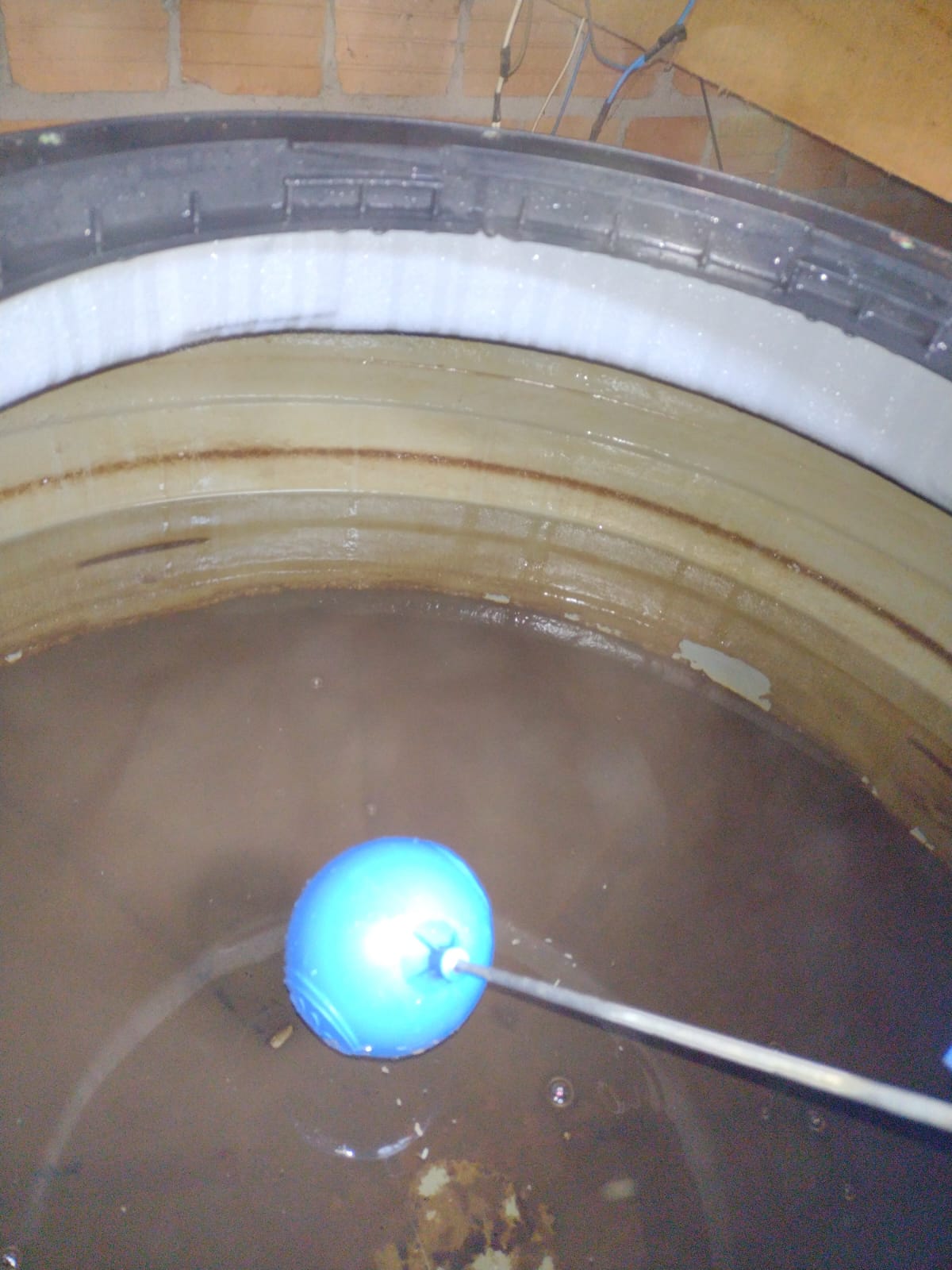 Interior de caixa d'água com água escura e paredes com lodo antes da limpeza